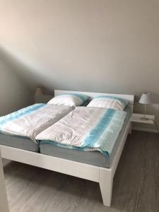 a bed with blue and white sheets and pillows at Schleiglück in Rieseby
