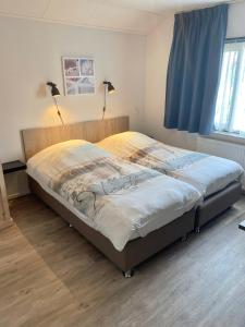 a bedroom with a large bed with two lamps on it at Pension Brinkvis in De Koog