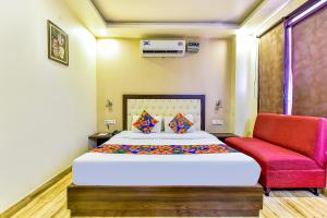 a bedroom with a bed and a red chair at Hotel Surya Residency in Dehradun