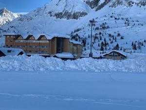 un bâtiment dans la neige à côté d'une montagne dans l'établissement Grand Hotel Miramonti, à Passo del Tonale