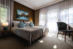 a bedroom with a bed and a chair and windows at Resort Dworzysko in Szczawno-Zdrój