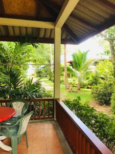 eine Veranda mit einem Tisch und Stühlen sowie einen Garten in der Unterkunft Hanalei Gardens in Mae Nam