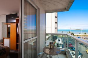 a balcony with a table and a view of the ocean at Hotel Santorini in Vila Velha