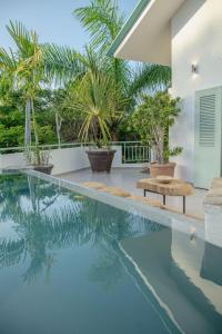 a swimming pool with palm trees and a house at Tropical Penthouse in the Heart of Las Terrenas! in Las Terrenas