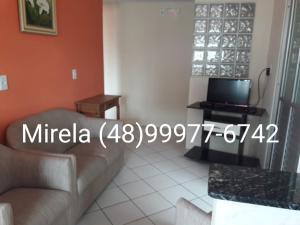 sala de estar con sofá y TV en Apartamento Praia dos Ingleses, 100 mt do mar, en Florianópolis