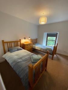 a bedroom with two beds and a dresser and a window at Charleton Farm Cottages in Montrose