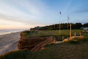 a sandy beach with a fence and the ocean at Tillicum Beach Motel - Formerly Deane's Oceanfront Lodge in Yachats