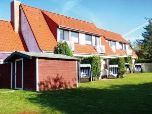 Grödersby的住宿－FeWo Woge，一座带橙色屋顶和绿色庭院的房子
