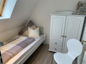 GrödersbyにあるFeWo Wogeの小さなベッドルーム(ベッド1台、白い椅子2脚付)