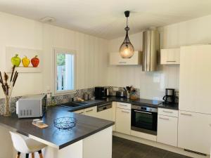 a kitchen with white cabinets and a black counter top at Maison de la forêt, terrasse plein sud et standing in Saint-Jean-de-Monts