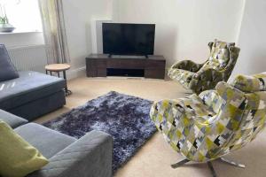 un salon avec un canapé, des fauteuils et une télévision dans l'établissement Ulverston South Lakes Spacious 3 Bed G/F Apartment, à Ulverston