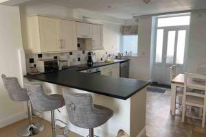 a kitchen with a black counter top and some chairs at Ulverston South Lakes Spacious 3 Bed G/F Apartment in Ulverston
