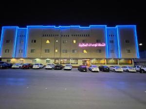 ein großes Gebäude mit Autos auf einem Parkplatz in der Unterkunft الشعلة للشقق المفروشة in Riad