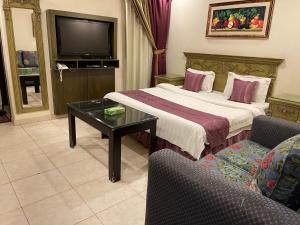 ein Hotelzimmer mit einem Bett und einem TV in der Unterkunft الشعلة للشقق المفروشة in Riad