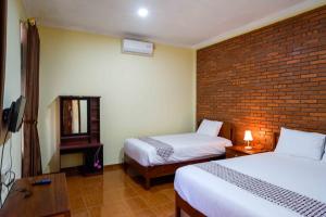 a hotel room with two beds and a brick wall at Roemah Beong Syariah at Desa Wisata Kembanglimus Mitra RedDoorz in Magelang
