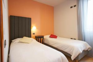 2 camas en una habitación con paredes de color naranja en Hotel Milano & Apartments en Miazzina