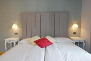 a white bed with two pillows on it with two lights at Hotel Milano & Apartments in Miazzina