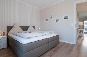 ハイリゲンハーフェンにあるOstsee - Appartement Nr 152 "11 Ost" im Strand Resortの白いベッドルーム(白いシーツ付きのベッド1台付)