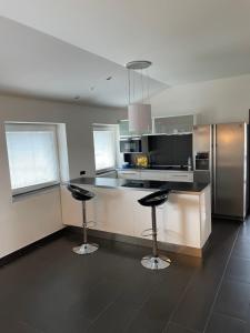 a kitchen with two bar stools and a stainless steel refrigerator at Penzion FAJN *** in Pardubice