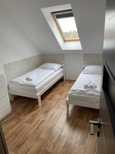 two beds in a small room with a window at Penzion FAJN *** in Pardubice