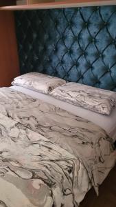 un lit avec une tête de lit capitonnée bleue et un matelas dans l'établissement Apartman Ema, à Valjevo