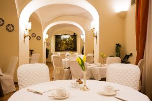 a restaurant with white tables and chairs and a painting at Palazzo Alabardieri in Naples