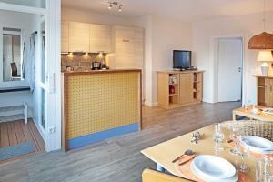 un salon avec une cuisine et une table avec des assiettes dans l'établissement Pure Wonne Mandoe, à List auf Sylt