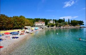a beach with umbrellas and people in the water at Ikar Apartment in Ika +10 photos