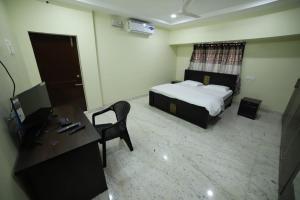 a bedroom with a bed and a desk and a computer at Royal Home Stay deluxe Room in Tirupati
