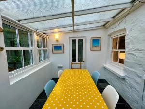 uma mesa amarela e cadeiras num quarto com janelas em Mapa Cottage em Mount Hawke