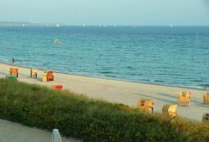 - une plage avec des tables et des chaises sur l'eau dans l'établissement Fehmarn- Ostseeferien FeWo Prusseit171, à Burgtiefe auf Fehmarn 
