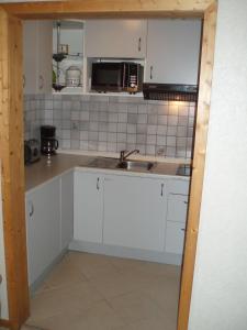 a kitchen with white cabinets and a sink at Ferienhaus Astrid in Osteel