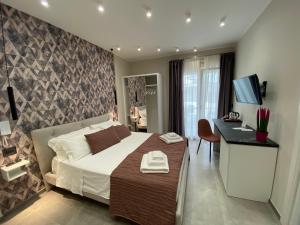 een slaapkamer met een bed en een bureau met een televisie bij Liberty Lodge in Tropea