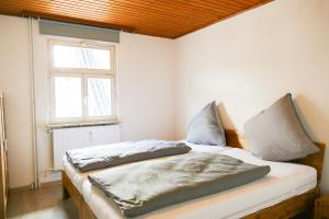 a bedroom with a bed with two pillows and a window at Ferienwohnung Neu "Zum Westerwald" LAHN02 in Löhnberg