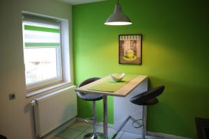 une salle verte avec une table et deux tabourets dans l'établissement Modernes Ruhrgebietsdomizil, à Hattingen