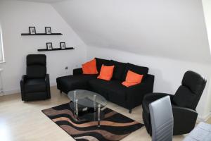 a living room with a black couch and two chairs at Modernes Ruhrgebietsdomizil in Hattingen