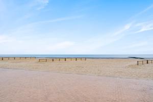 a sandy beach with a row of wooden barriers at Refurbished comfortable app 1min from the sea in Koksijde