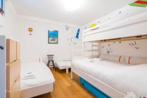 two beds in a room with white walls and wooden floors at Refurbished comfortable app 1min from the sea in Koksijde