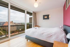 a bedroom with a bed and a large window at Refurbished comfortable app 1min from the sea in Koksijde