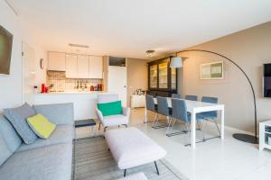 a living room with a couch and a table and chairs at Refurbished comfortable app 1min from the sea in Koksijde