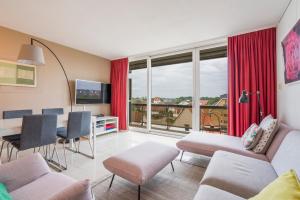 a living room with a couch and a table with chairs at Refurbished comfortable app 1min from the sea in Koksijde
