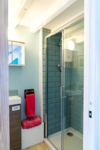 a bathroom with a glass shower with a red seat at Bwthyn Gweilch in Machynlleth