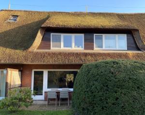 a thatch roofed house with a table and chairs at Warfthüs in Sankt Peter-Ording