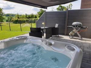 a hot tub in a backyard with a table and a grill at Eifel Dream Kalkmulde in Fleringen