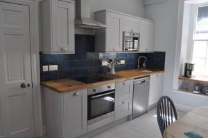 a kitchen with white cabinets and blue tiles on the wall at Luxury dog friendly home in Brixham harbour with sea views and free parking in Brixham