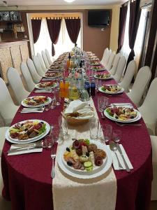 un lungo tavolo con piatti di cibo sopra di Hanul La Cetate - Cazare pentru muncitori și delegați a Slimnic