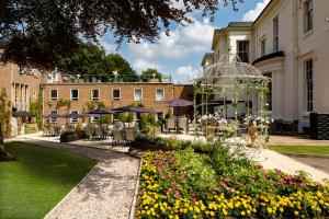 a garden with chairs and flowers in front of a building at RainHill Hall Hotel in Rainhull