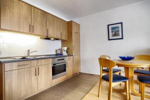 a kitchen with wooden cabinets and a table and a sink at Ostsee-Residenz Whg 12 in Zingst