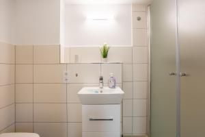 a white bathroom with a sink and a shower at Gästezimmer Teltow in Teltow