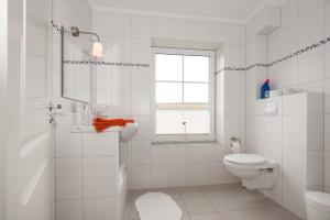 a white bathroom with a toilet and a window at Wohnung 1 in Fehmarn